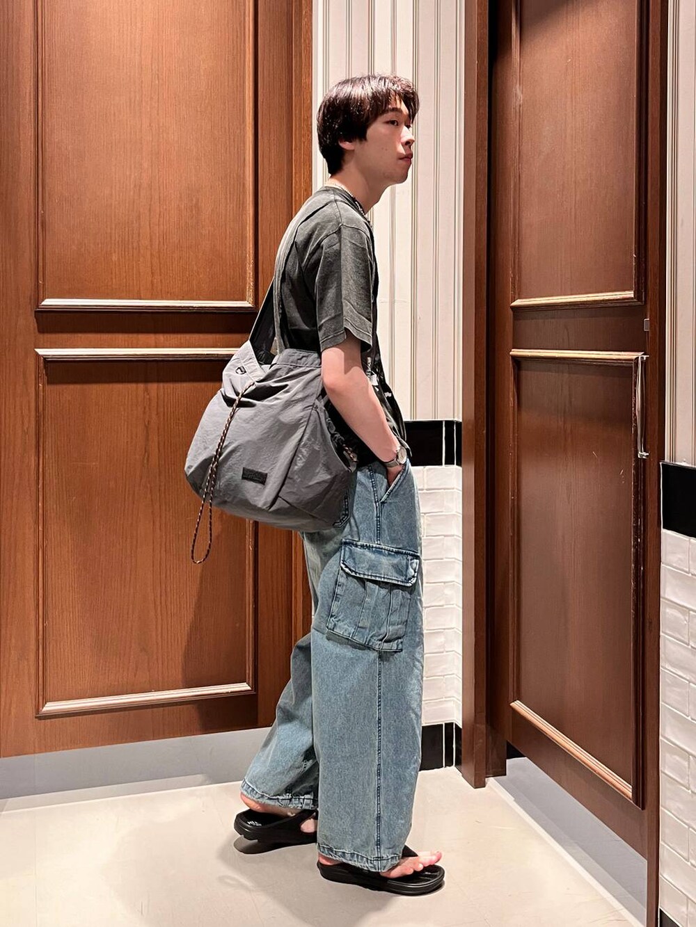 ブラック系のサンダル、ブルー系のデニムパンツ、ブラック系のショルダーバッグを着用したメンズの夏コーディネートの5枚目の写真