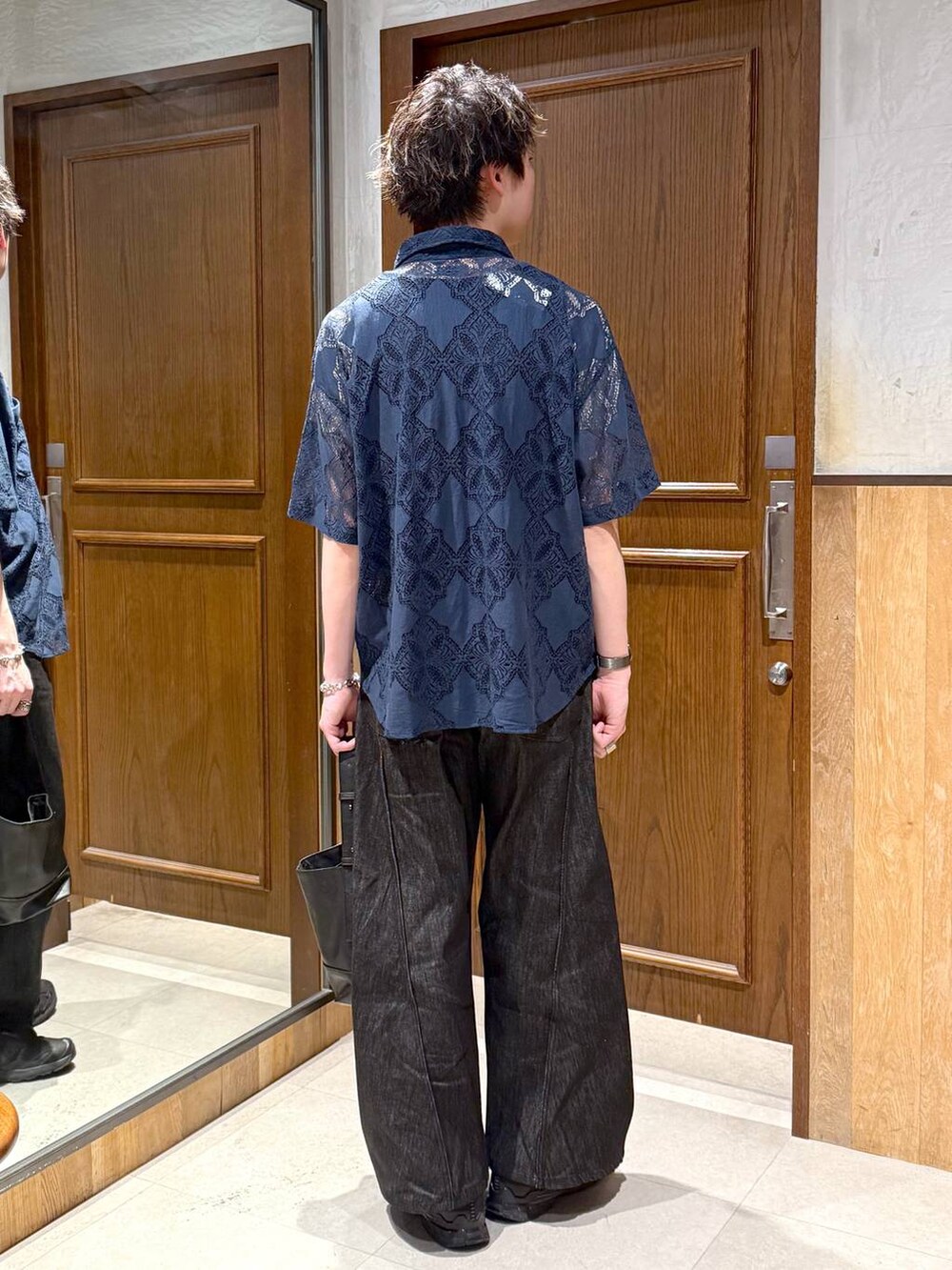 ブラック系のハンドバッグ、ブラック系のデニムパンツ、ブルー系のシャツ/ブラウスを着用したメンズの春コーディネートの3枚目の写真