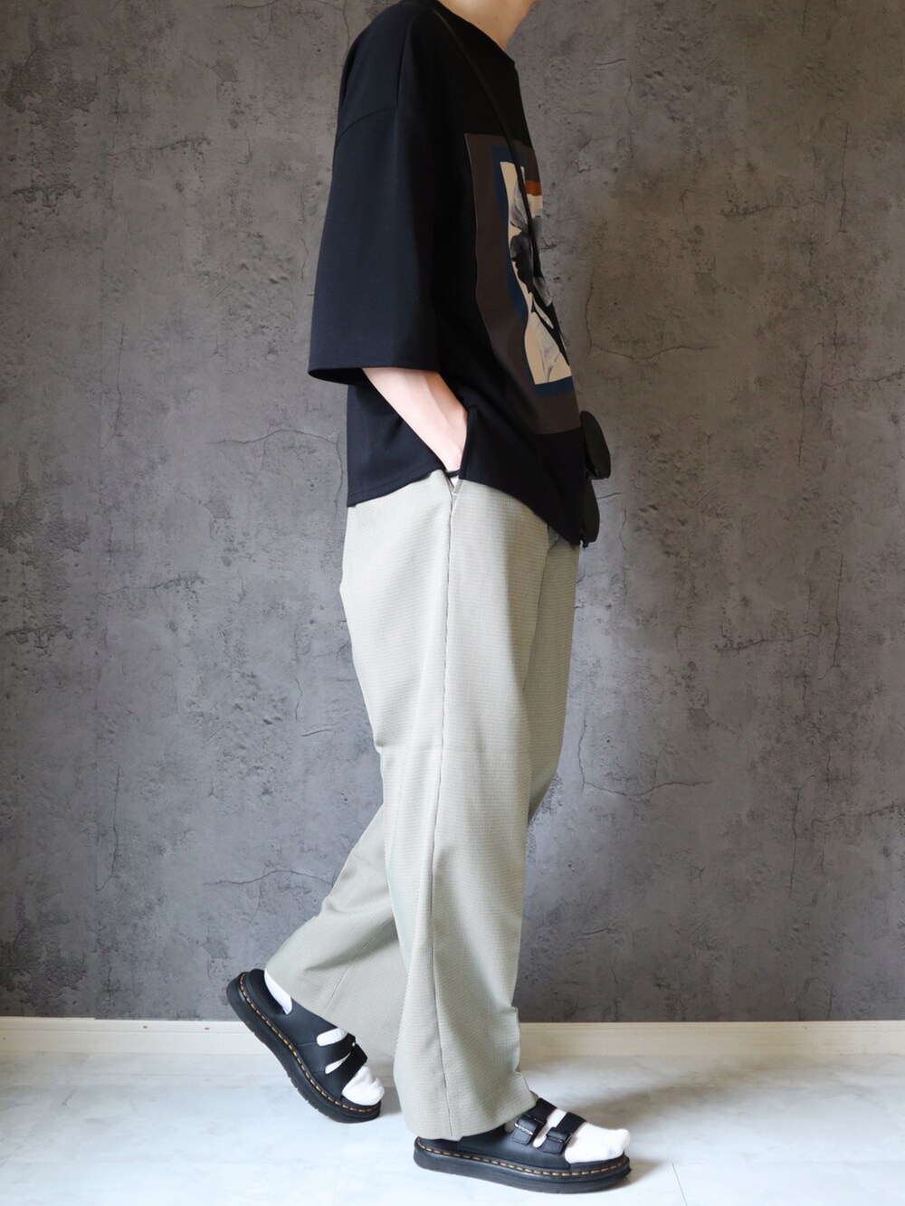 ブラック系のTシャツ/カットソー、ベージュ系のスラックス、ブラック系のサンダルを着用したメンズの夏コーディネートの3枚目の写真