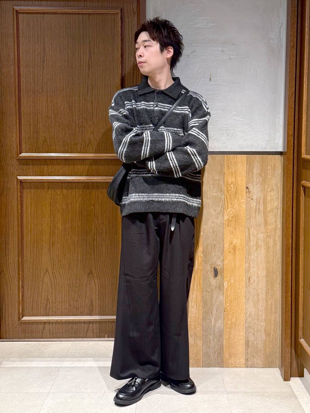 ブラック系のショルダーバッグ、ブラック系のポロシャツ、ブラック系のスラックスを着用したメンズの冬コーディネートの3枚目の写真