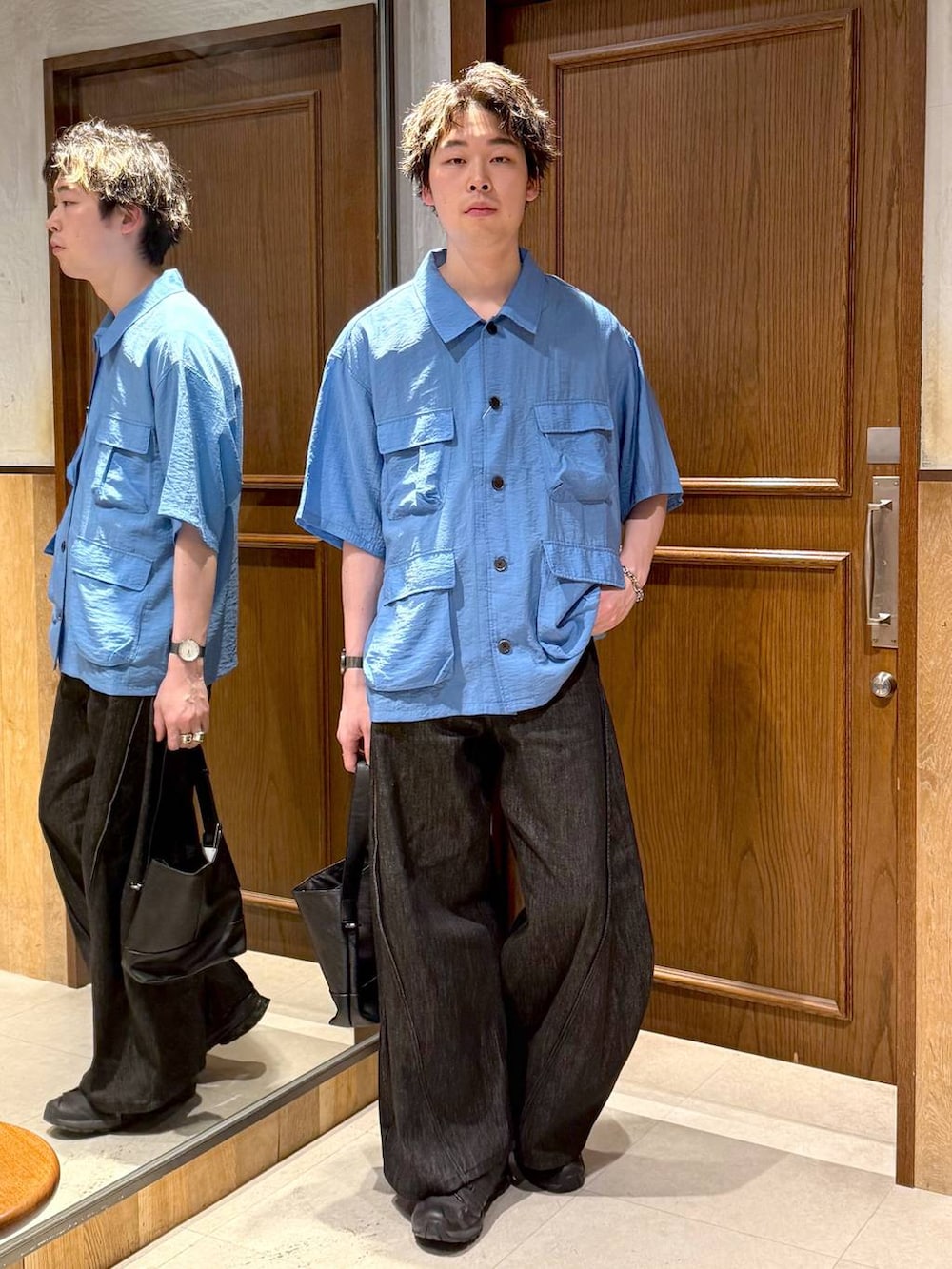 ブラック系のハンドバッグ、ブラック系のデニムパンツ、ブルー系のシャツ/ブラウスを着用したメンズの春コーディネートの2枚目の写真