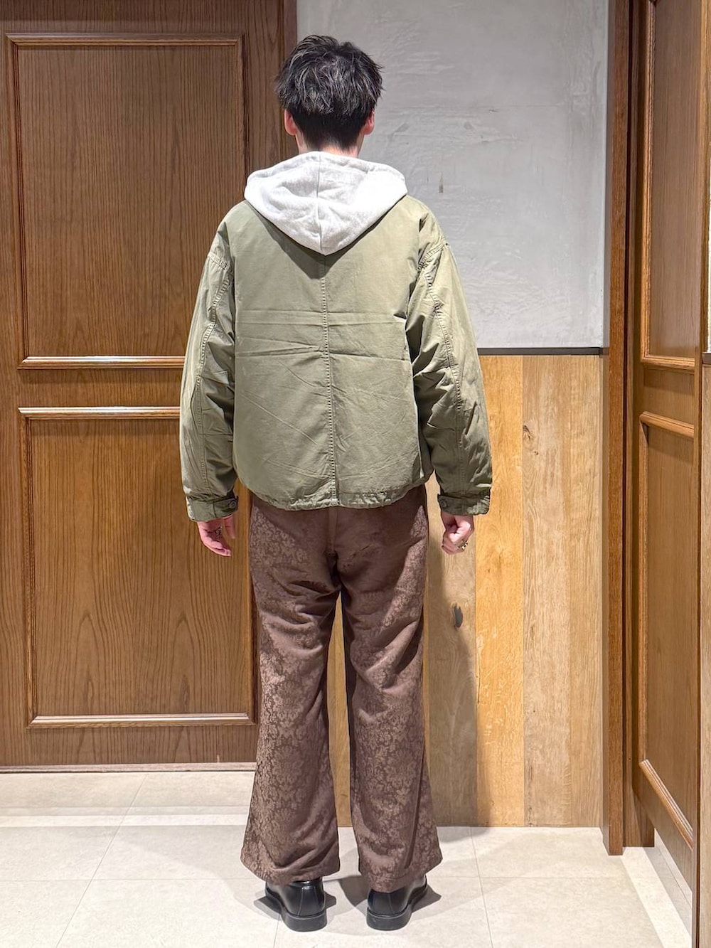 グリーン系のモッズコート、イエロー系のスラックス、グレー系のパーカーを着用したメンズの冬コーディネートの5枚目の写真