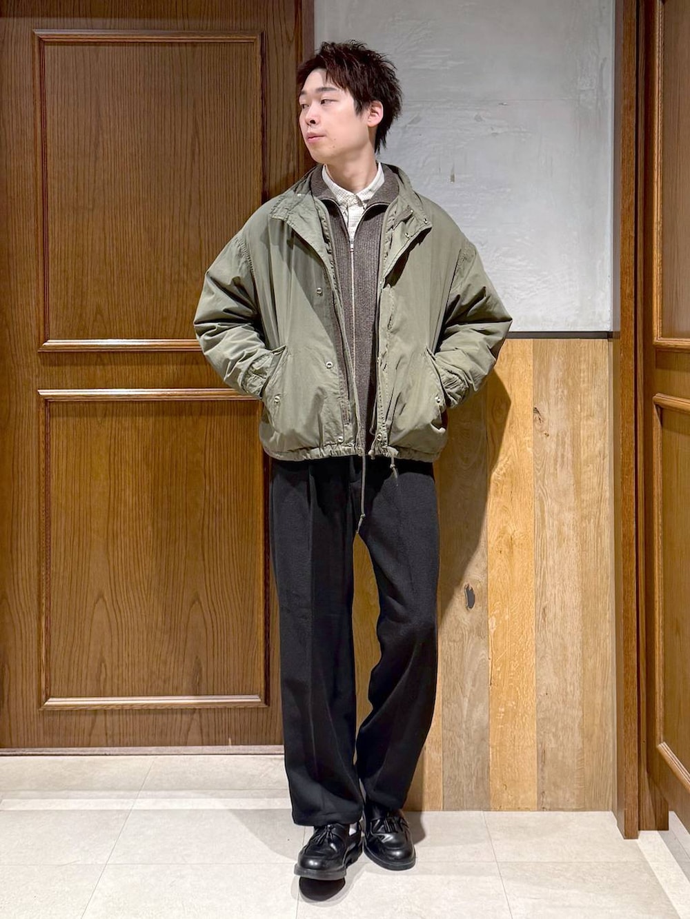 グリーン系のモッズコート、ブラック系のスラックス、ホワイト系のシャツ/ブラウスを着用したメンズの冬コーディネートの3枚目の写真