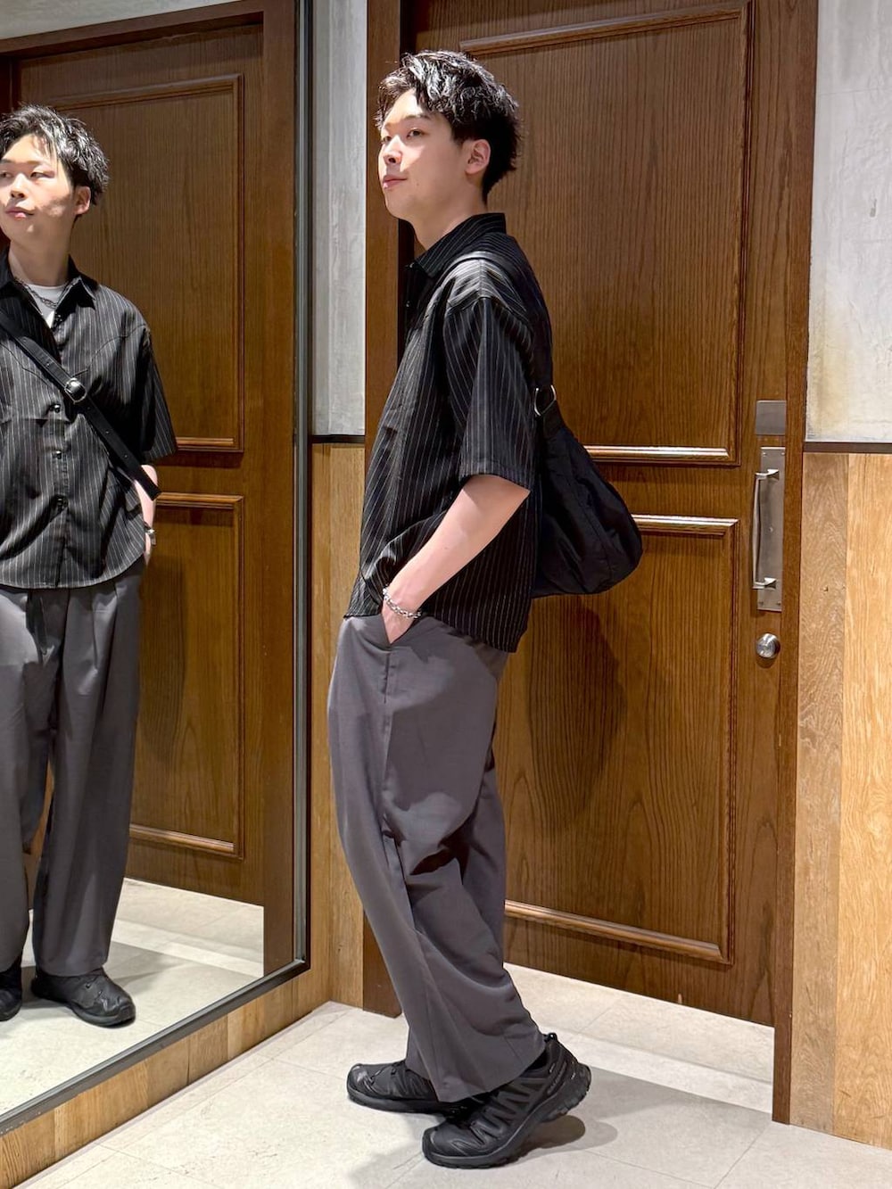 グレー系のスラックス、ブラック系のショルダーバッグ、ホワイト系のTシャツ/カットソーを着用したメンズの春コーディネートの3枚目の写真