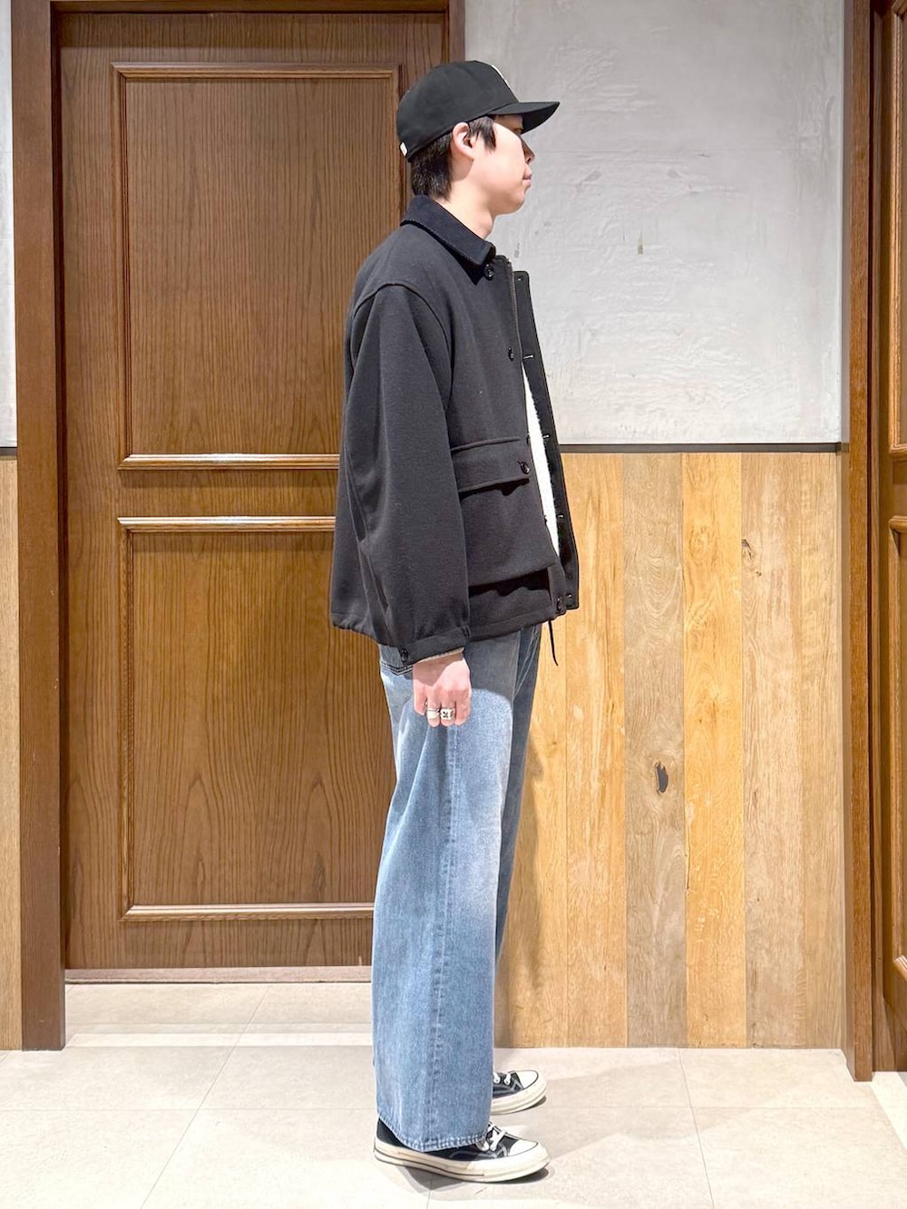 ブラック系のブルゾン、ホワイト系のニット/セーター、ブルー系のデニムパンツを着用したメンズの冬コーディネートの6枚目の写真