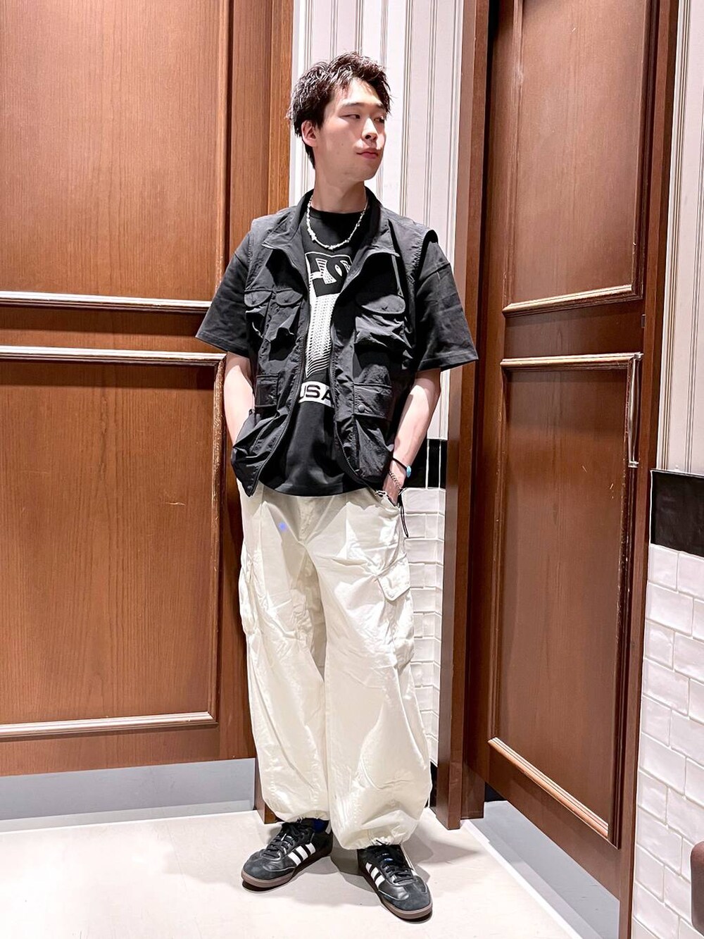 ホワイト系のカーゴパンツ、ブラック系のベスト、ブラック系のTシャツ/カットソーを着用したメンズの夏コーディネートの2枚目の写真