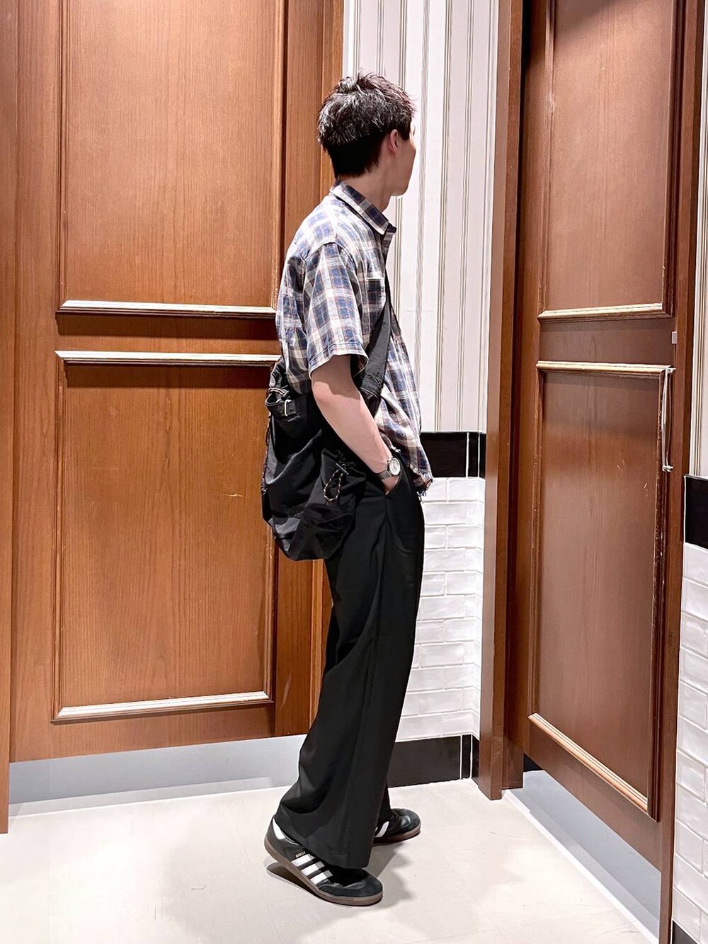 ブラック系のスラックス、ブラック系のショルダーバッグ、ブルー系のシャツ/ブラウスを着用したメンズの夏コーディネートの5枚目の写真