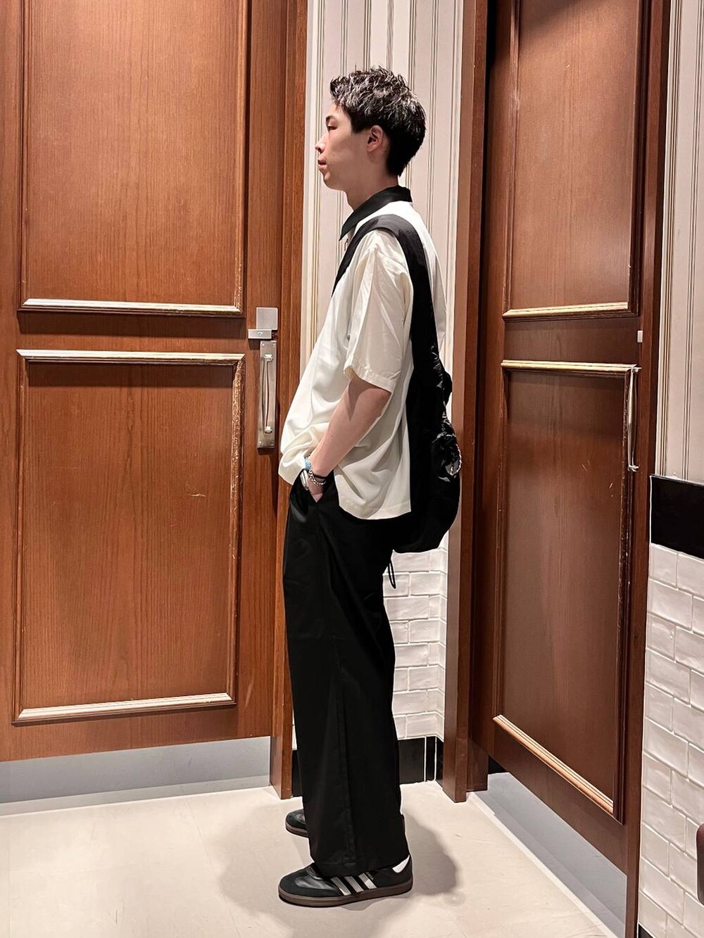 ブラック系のスラックス、ブラック系のショルダーバッグ、ホワイト系のシャツ/ブラウスを着用したメンズの夏コーディネートの3枚目の写真