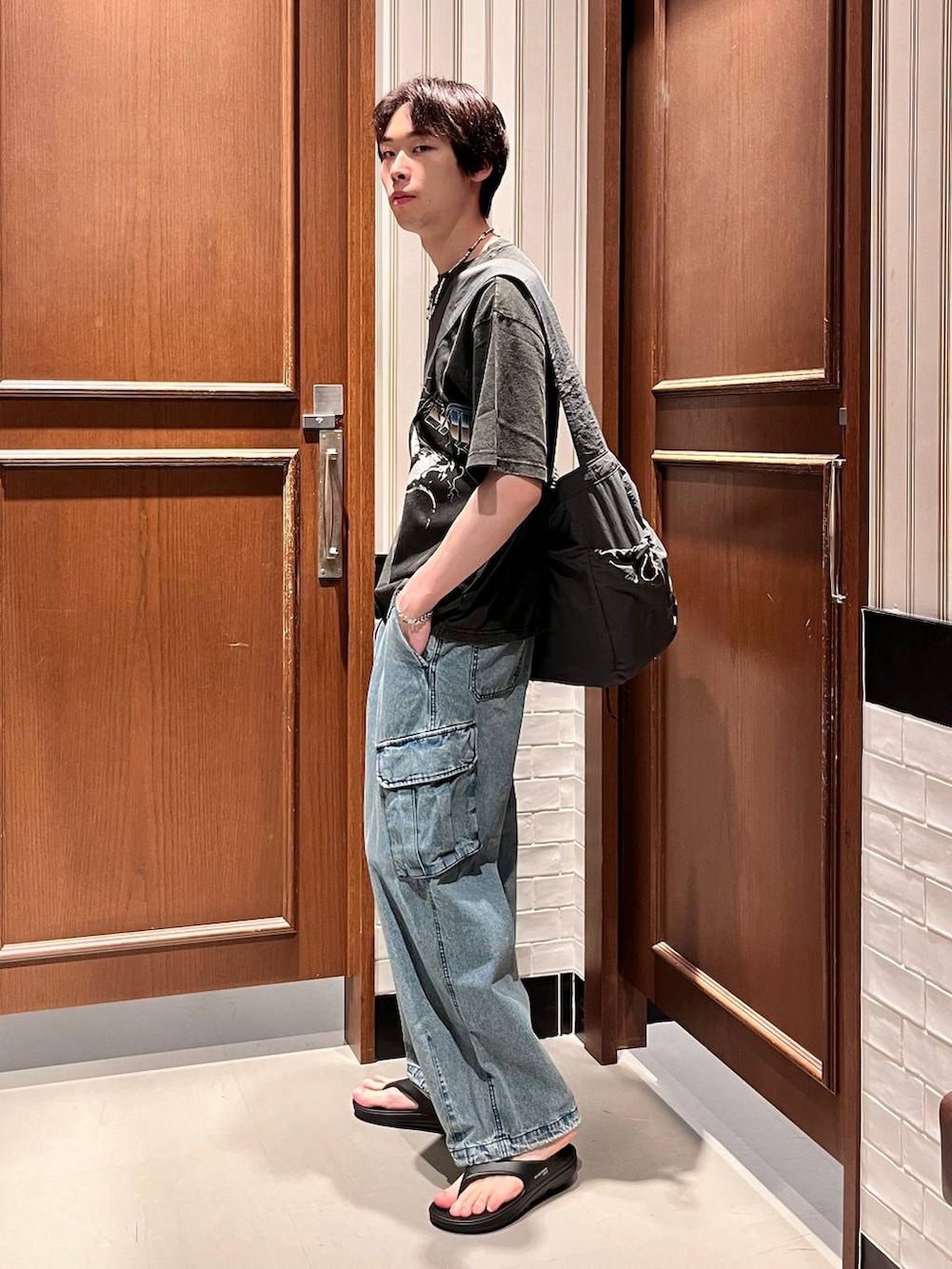 ブラック系のサンダル、ブルー系のデニムパンツ、ブラック系のショルダーバッグを着用したメンズの夏コーディネートの2枚目の写真