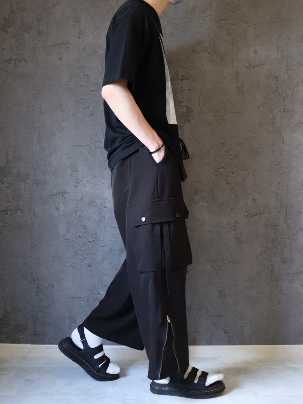 ブラック系のTシャツ/カットソー、ブラック系のカーゴパンツ、ブラック系のサンダルを着用したメンズの夏コーディネートの3枚目の写真