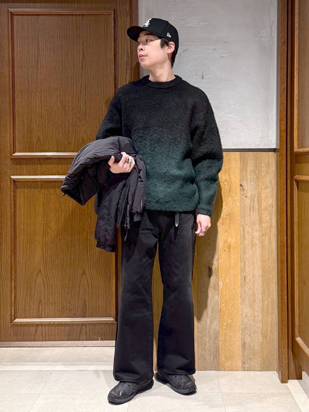 ブラック系のデニムパンツ、グリーン系のニット/セーター、ブラック系のダウンジャケット/コートを着用したメンズの冬コーディネートの2枚目の写真