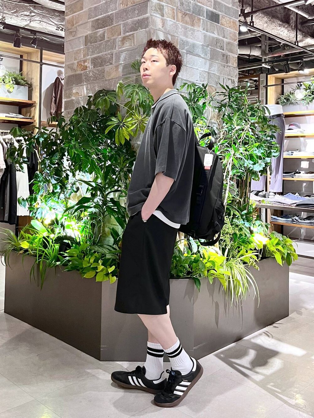 ブラック系のバックパック/リュック、ブラック系のスラックス、ホワイト系のタンクトップを着用したメンズの夏コーディネートの3枚目の写真