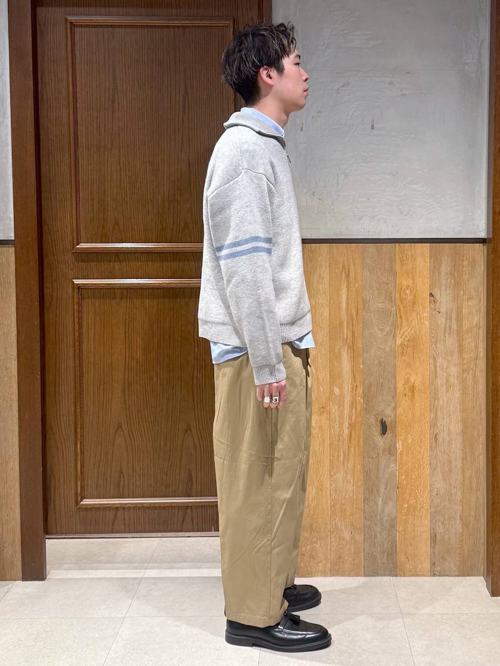 ブルー系のシャツ/ブラウス、ベージュ系のチノパンツ、グレー系のニット/セーターを着用したメンズの冬コーディネートの5枚目の写真