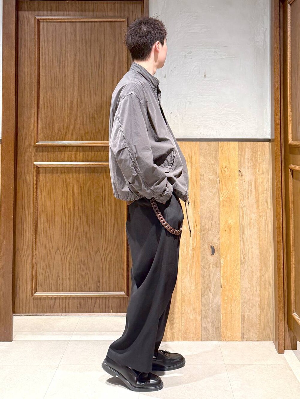 グレー系のモッズコート、ブラック系のスラックス、ブラウン系のスウェットを着用したメンズの秋コーディネートの6枚目の写真