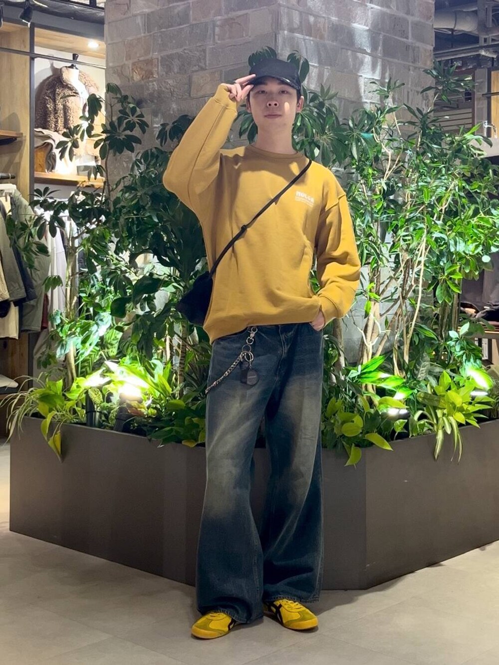 ブラック系のショルダーバッグ、ブルー系のデニムパンツ、イエロー系のスウェットを着用したメンズの秋コーディネートの4枚目の写真