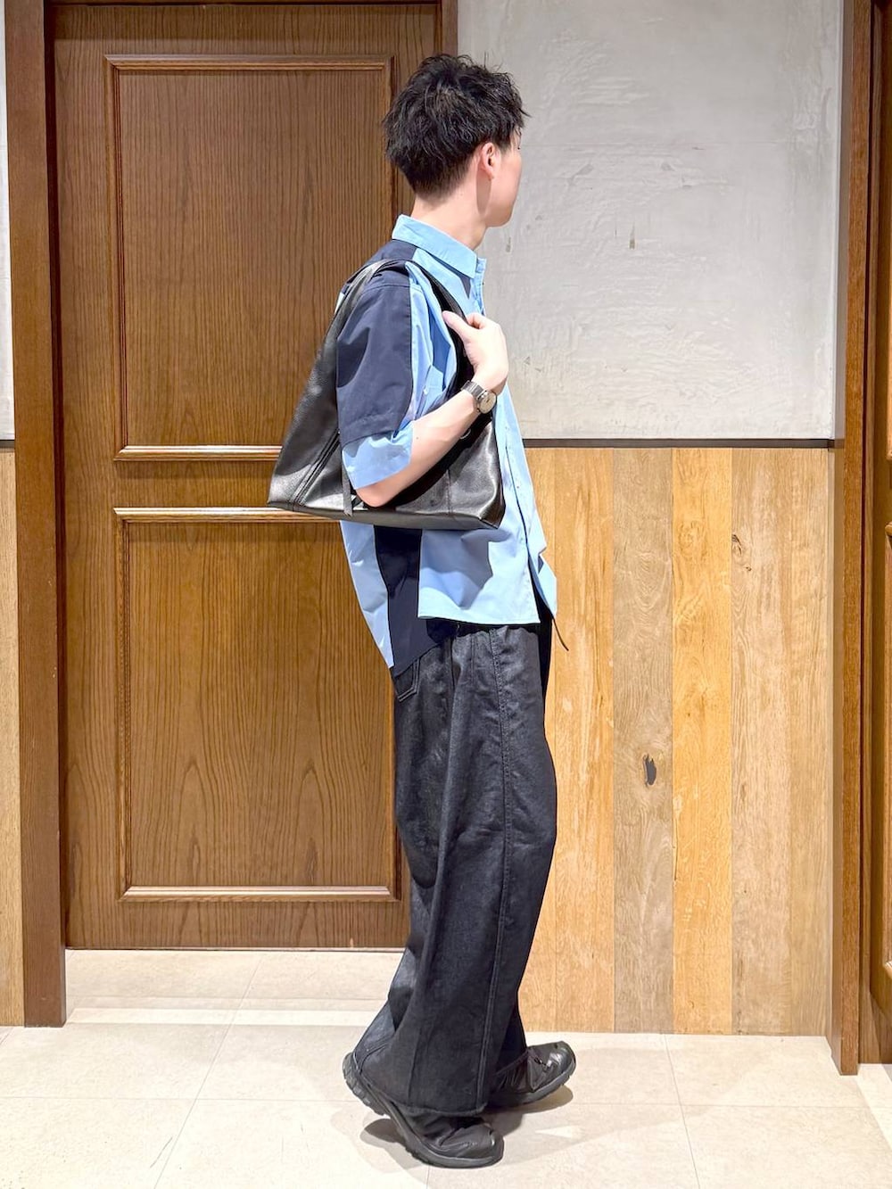 ブラック系のトートバッグ、ブルー系のデニムパンツ、ブルー系のシャツ/ブラウスを着用したメンズの春コーディネートの5枚目の写真