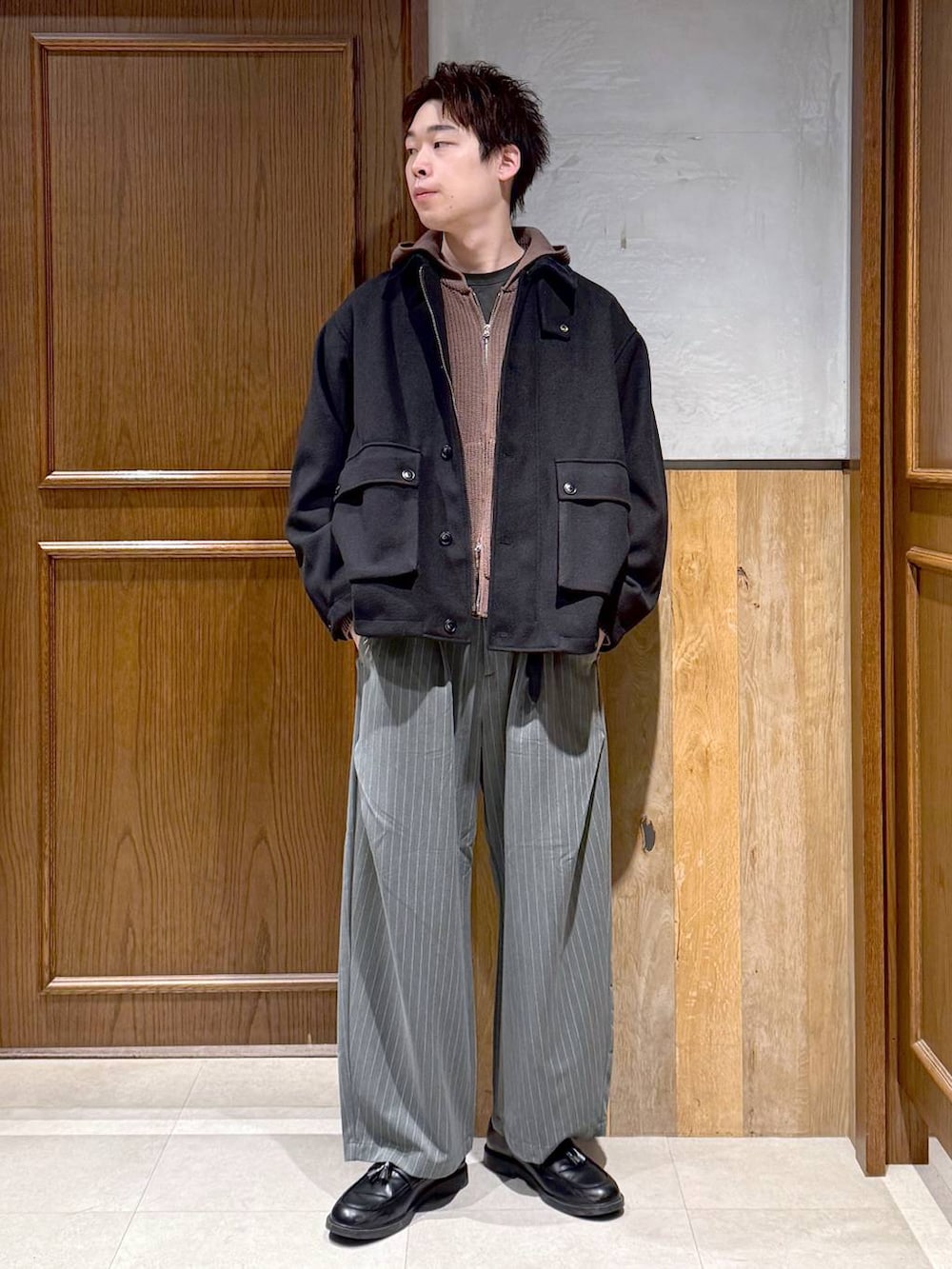 ブラック系のブルゾン、ブラウン系のニット/セーター、グレー系のスラックスを着用したメンズの冬コーディネートの8枚目の写真