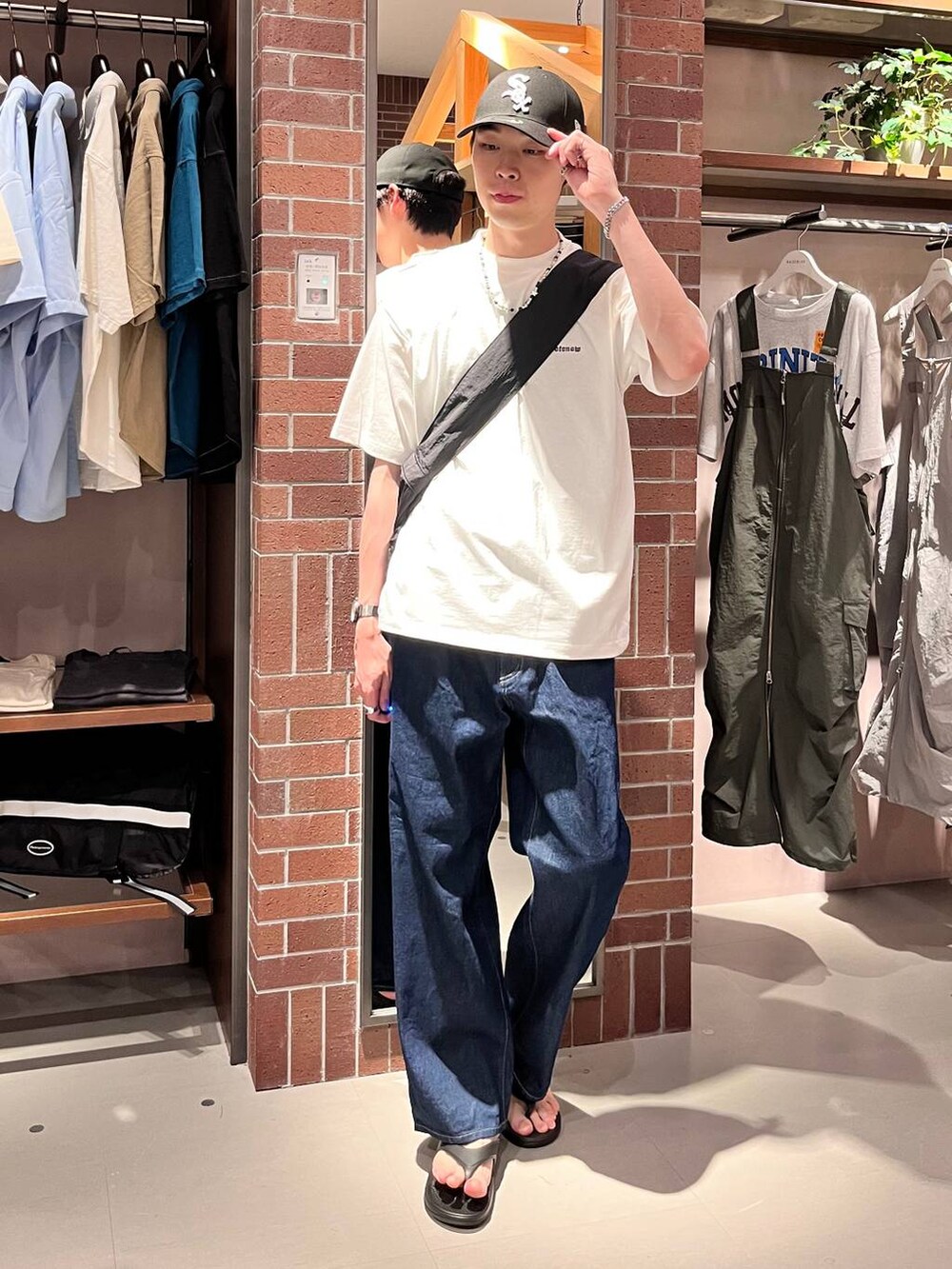 ブルー系のデニムパンツ、ブラック系のショルダーバッグ、ホワイト系のTシャツ/カットソーを着用したメンズの夏コーディネートの2枚目の写真