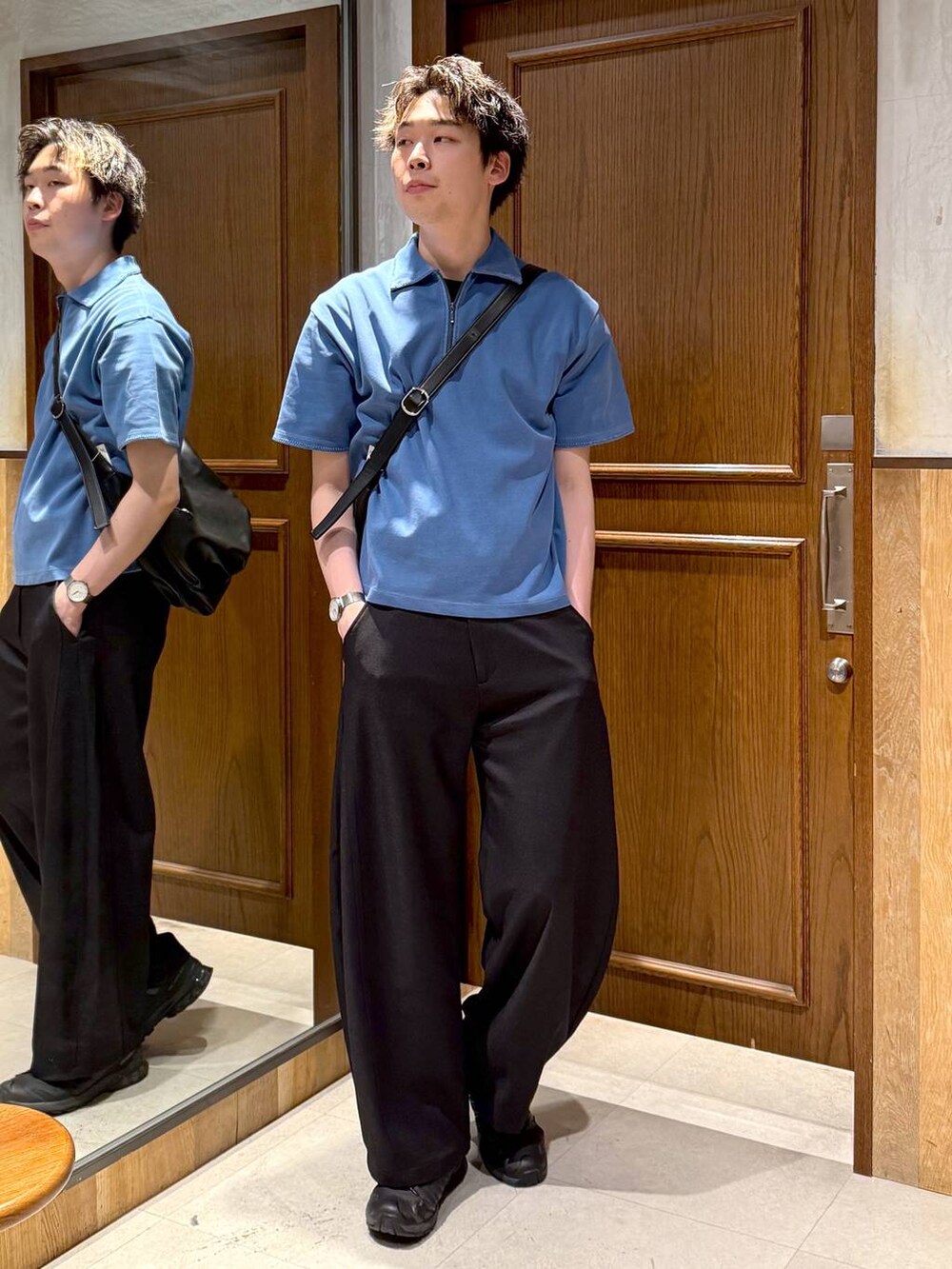 ブラック系のスラックス、ブラック系のショルダーバッグ、ブルー系のTシャツ/カットソーを着用したメンズの春コーディネートの7枚目の写真