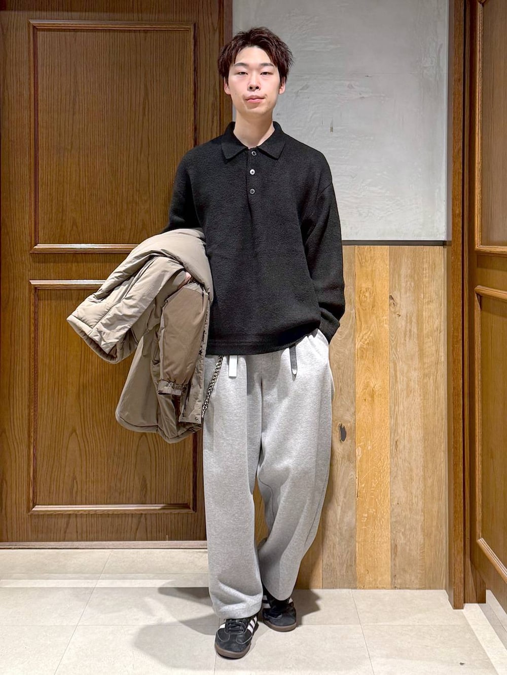 グリーン系のダウンジャケット/コート、ブラック系のポロシャツ、グレー系のスウェットパンツを着用したメンズの秋コーディネートの2枚目の写真