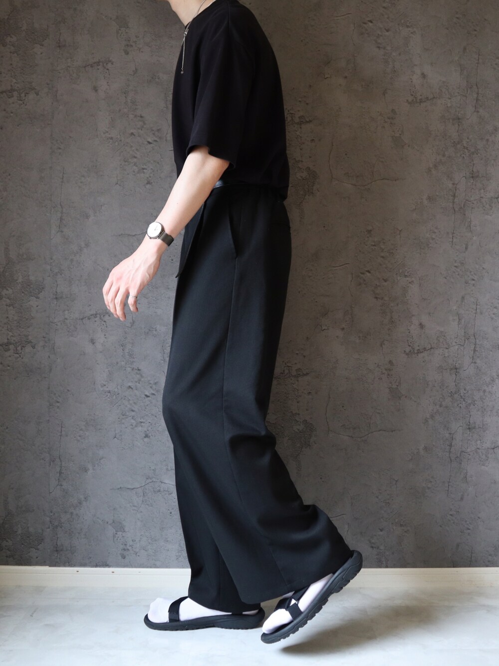 ブラック系のスラックス、ベージュ系のトートバッグ、ブラック系のサンダルを着用したメンズの夏コーディネートの3枚目の写真