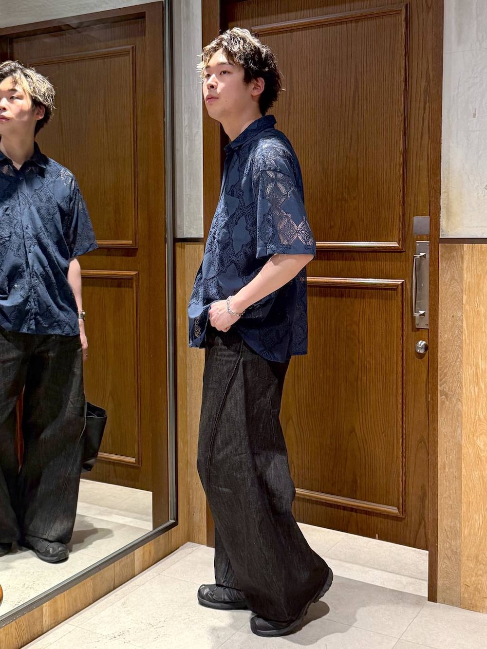 ブラック系のハンドバッグ、ブラック系のデニムパンツ、ブルー系のシャツ/ブラウスを着用したメンズの春コーディネートの2枚目の写真