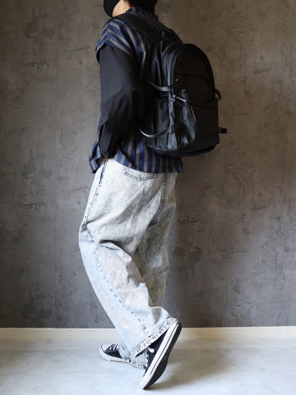 ブルー系のベスト、ブルー系のデニムパンツ、ブラック系のバックパック/リュックを着用したメンズの春コーディネートの3枚目の写真