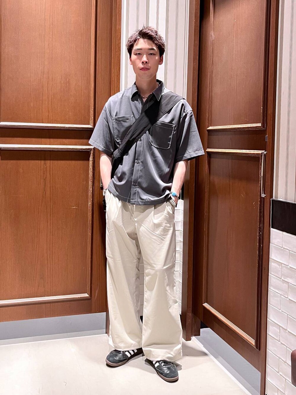 ホワイト系のスラックス、ブラック系のショルダーバッグ、グレー系のシャツ/ブラウスを着用したメンズの夏コーディネートの2枚目の写真