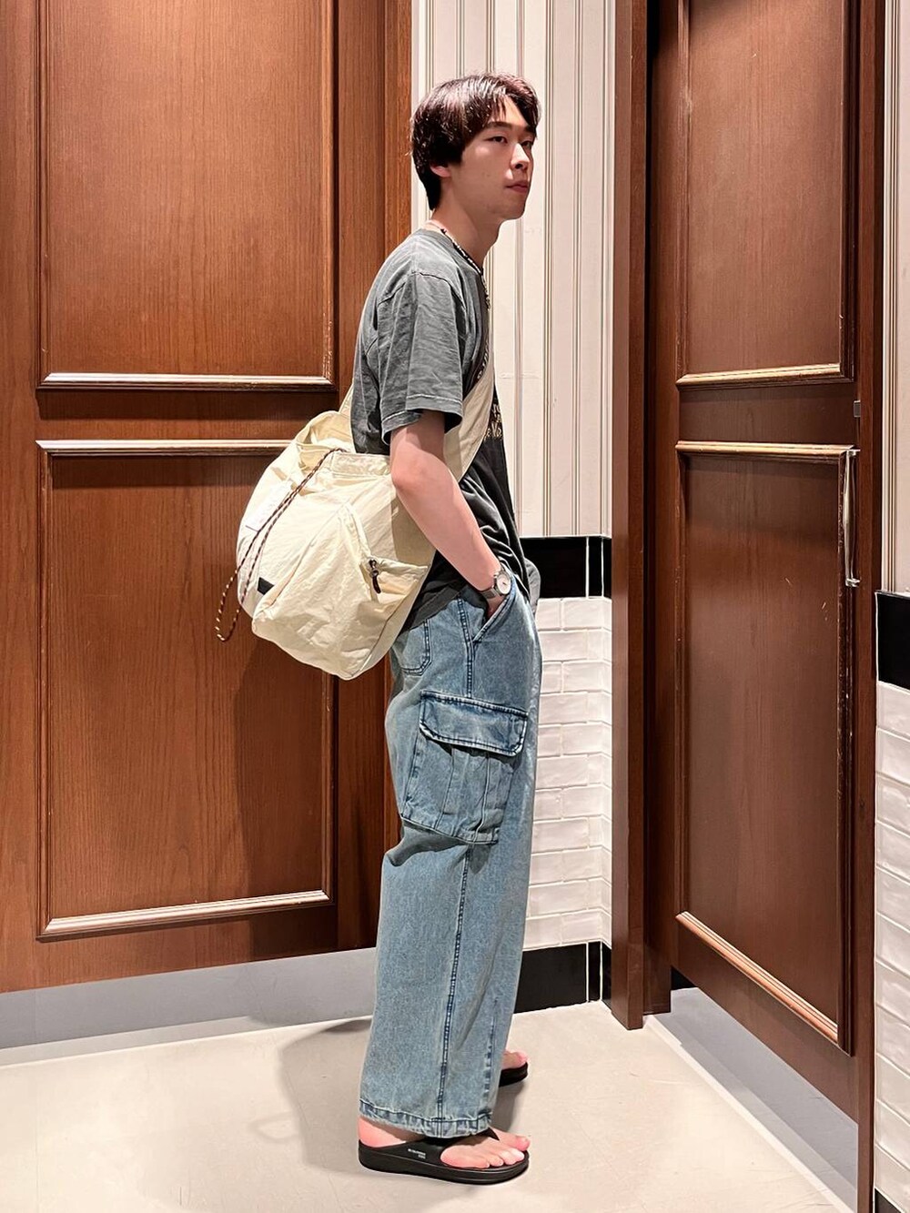 ブラック系のサンダル、ブルー系のデニムパンツ、ホワイト系のショルダーバッグを着用したメンズの夏コーディネートの4枚目の写真