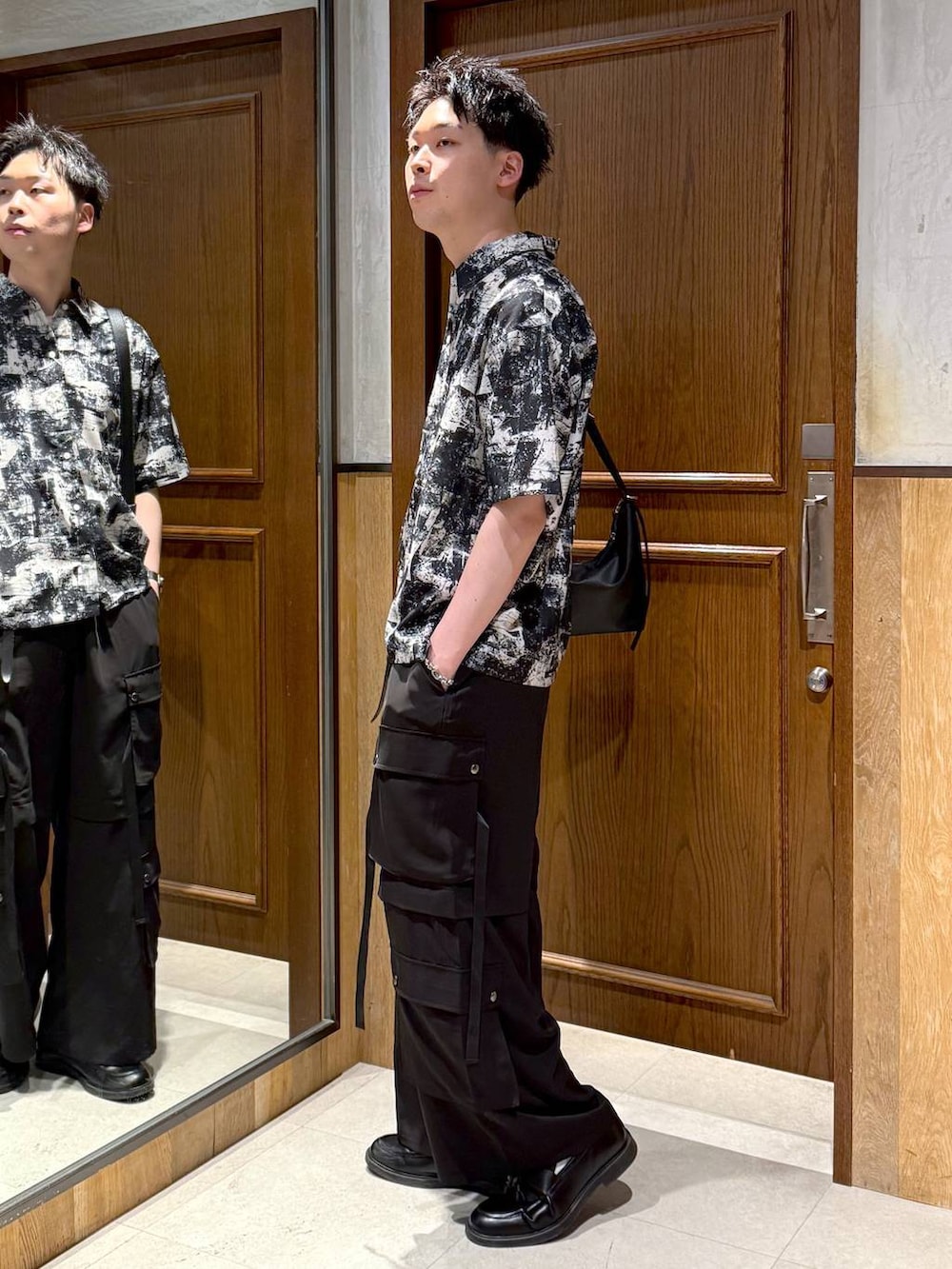 ブラック系のショルダーバッグ、ホワイト系のシャツ/ブラウス、ブラック系のカーゴパンツを着用したメンズの春コーディネートの3枚目の写真