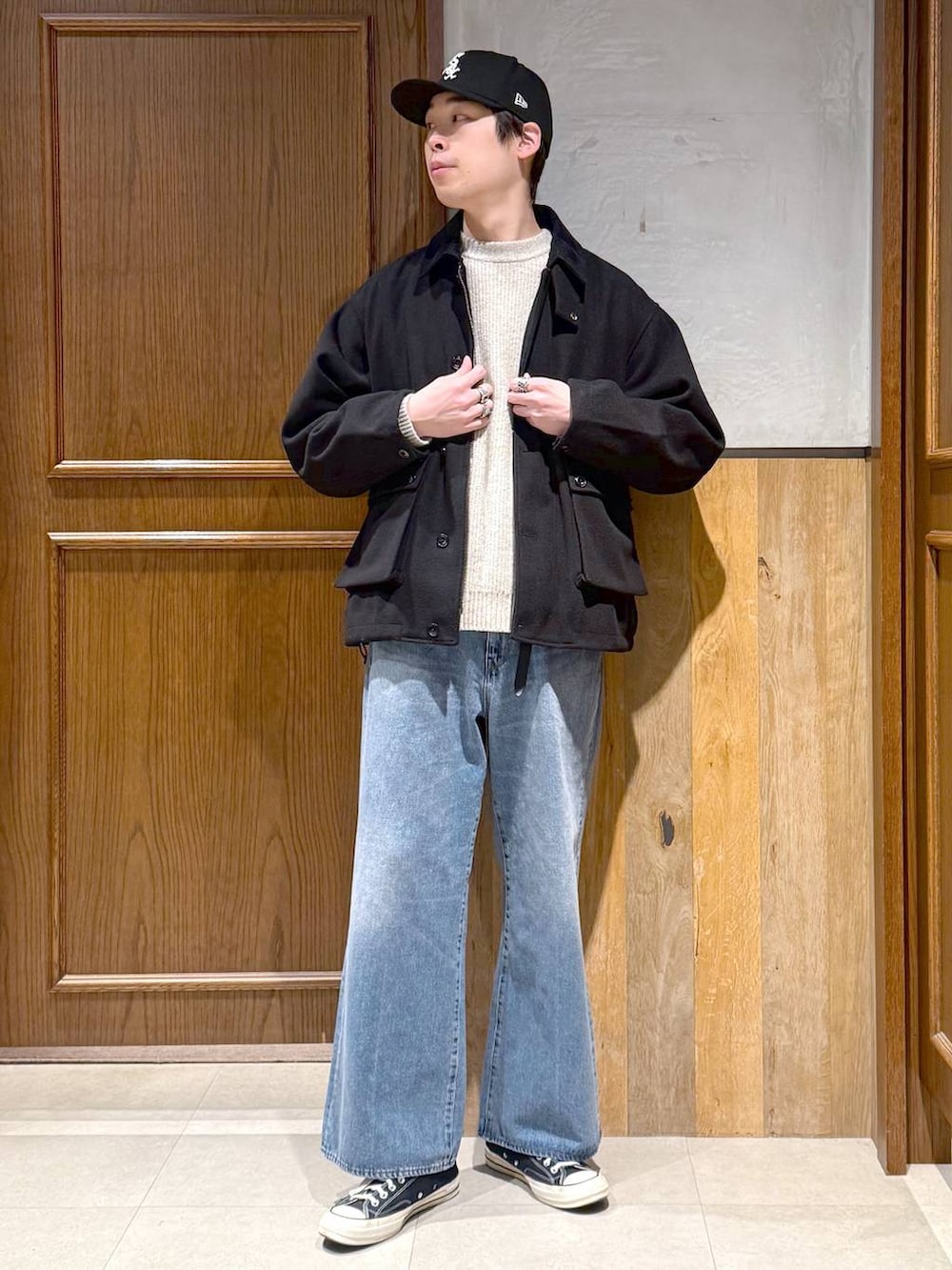 ブラック系のブルゾン、ホワイト系のニット/セーター、ブルー系のデニムパンツを着用したメンズの冬コーディネートの7枚目の写真