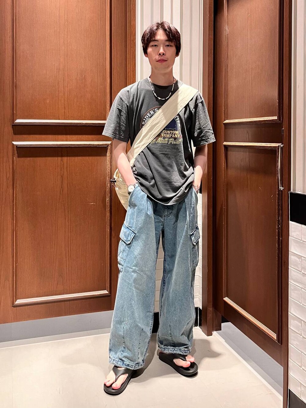 ブラック系のサンダル、ブルー系のデニムパンツ、ホワイト系のショルダーバッグを着用したメンズの夏コーディネートの7枚目の写真