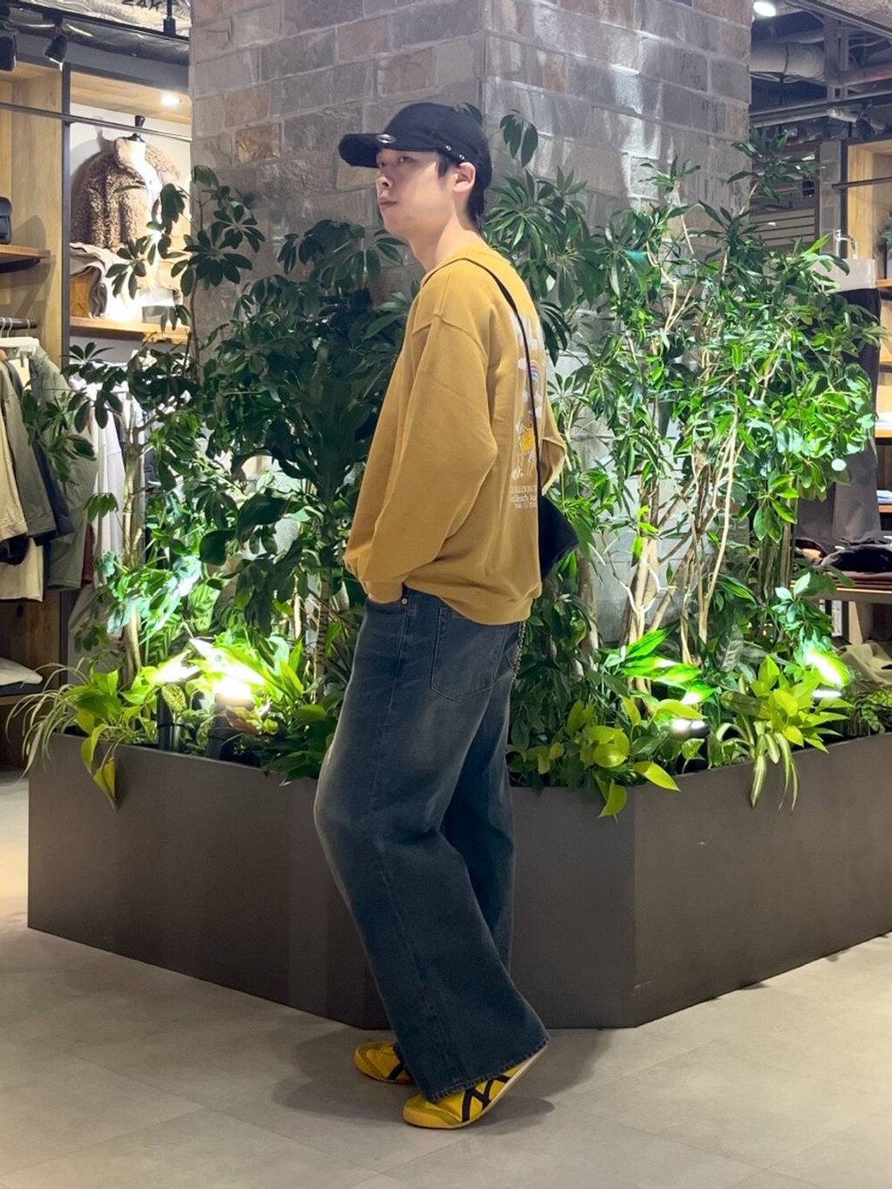 ブラック系のショルダーバッグ、ブルー系のデニムパンツ、イエロー系のスウェットを着用したメンズの秋コーディネートの2枚目の写真