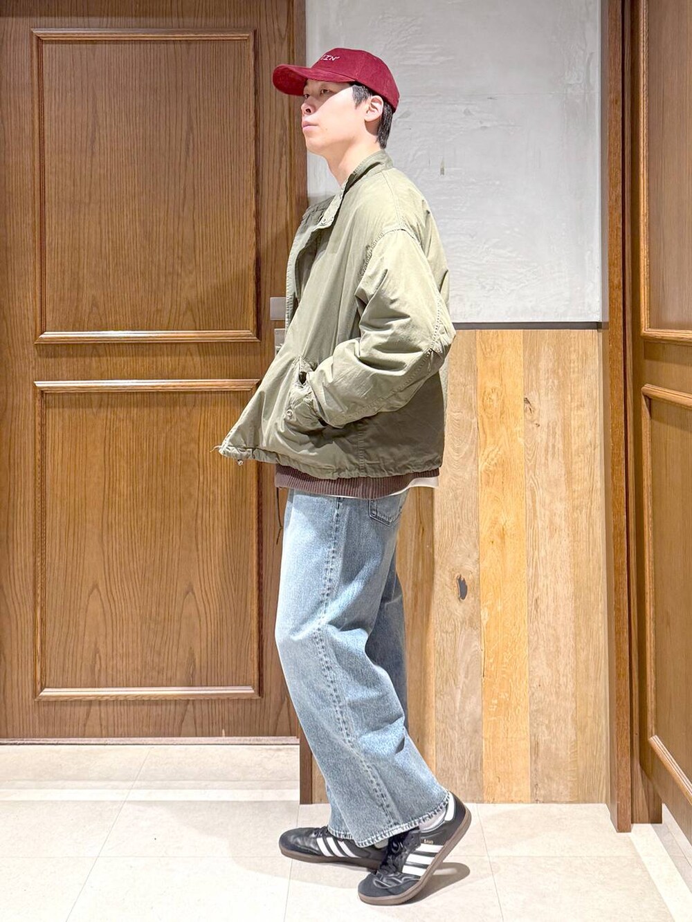 ブルー系のデニムパンツ、グリーン系のモッズコート、ブラウン系のカーディガン/ボレロを着用したメンズの秋コーディネートの5枚目の写真