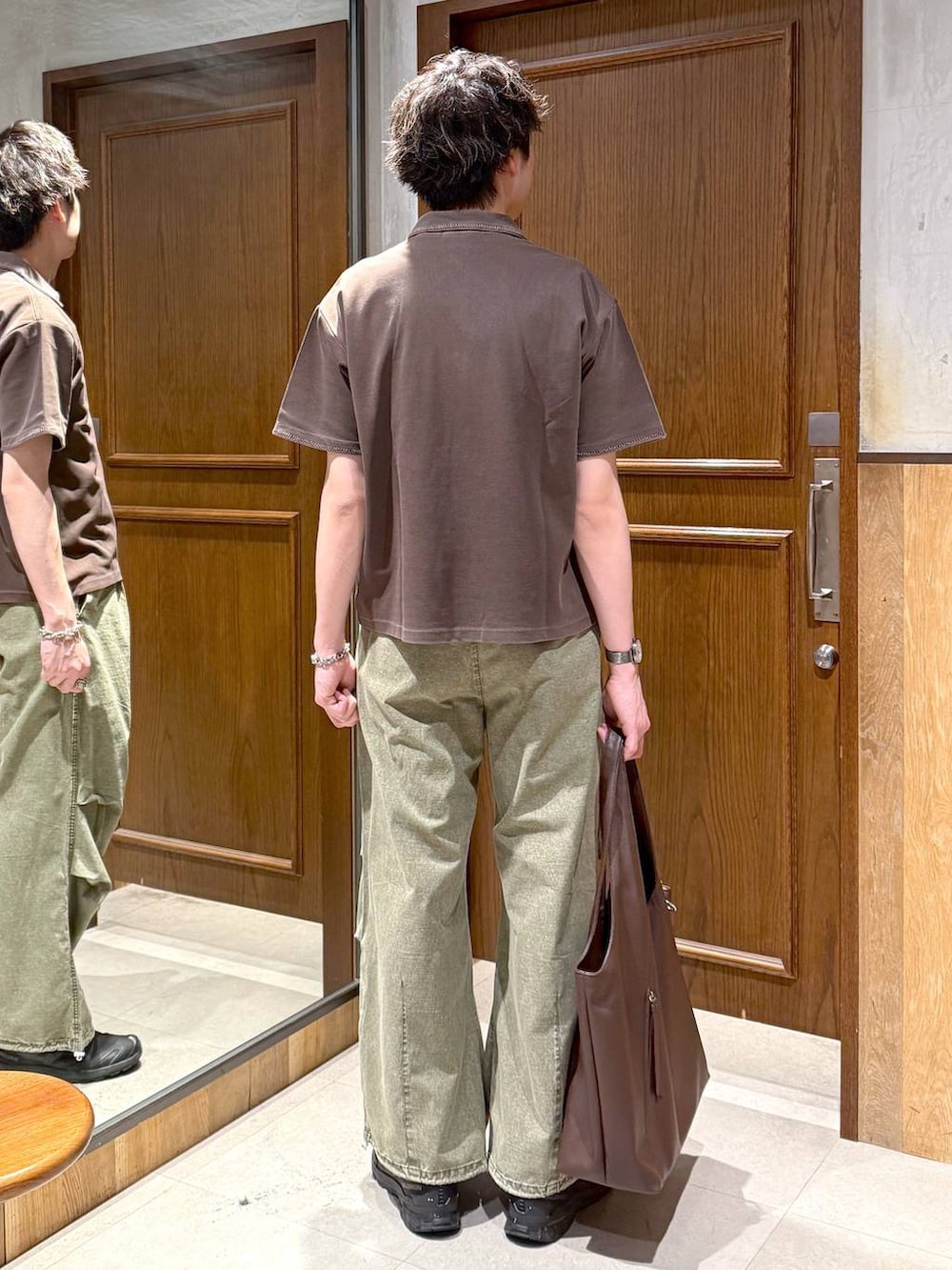 ブラウン系のトートバッグ、グリーン系のカーゴパンツ、ブラウン系のTシャツ/カットソーを着用したメンズの春コーディネートの4枚目の写真
