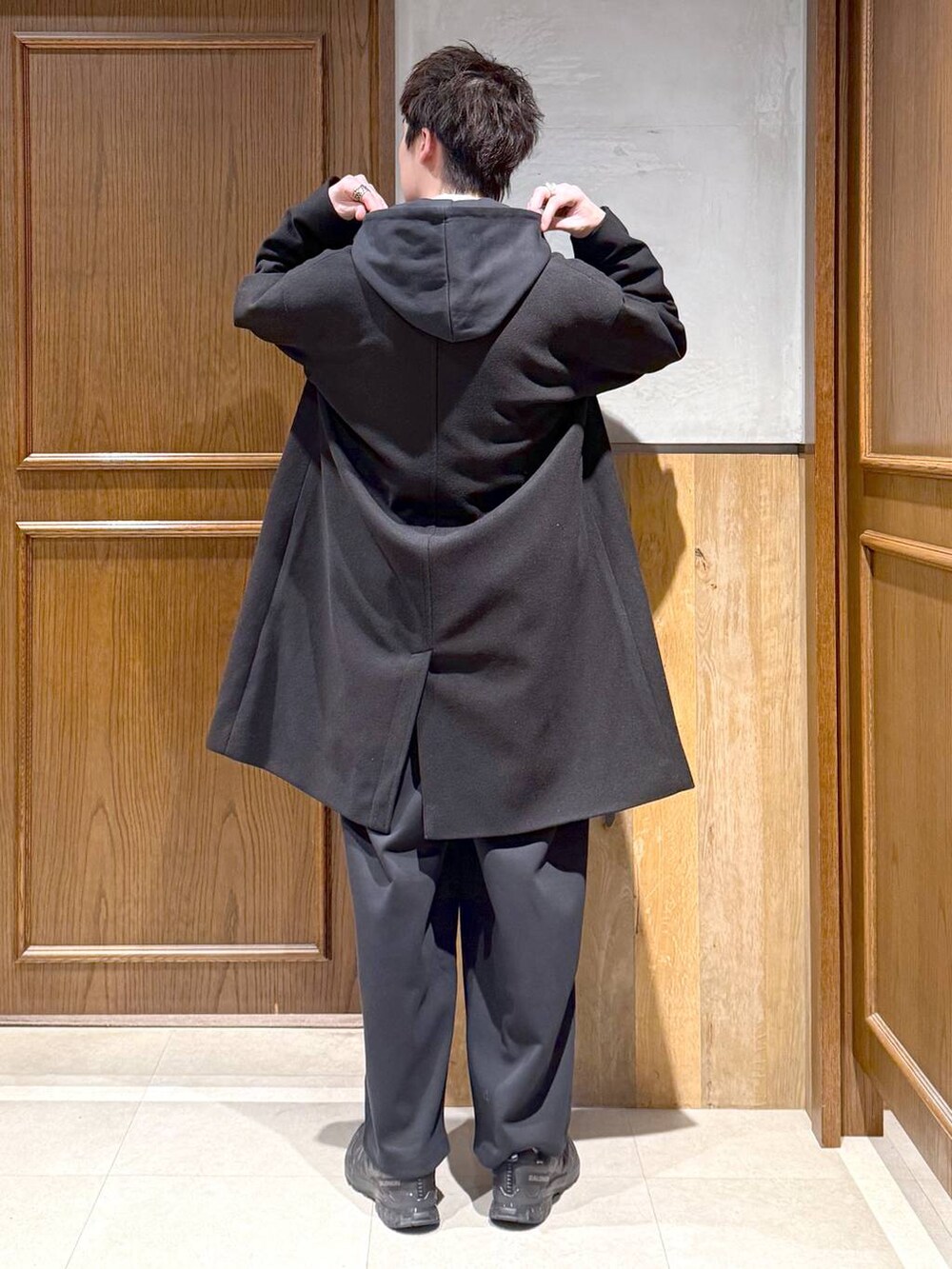 ブラック系のトレンチコート、ブルー系のシャツ/ブラウス、ブラック系のパーカーを着用したメンズの秋コーディネートの5枚目の写真