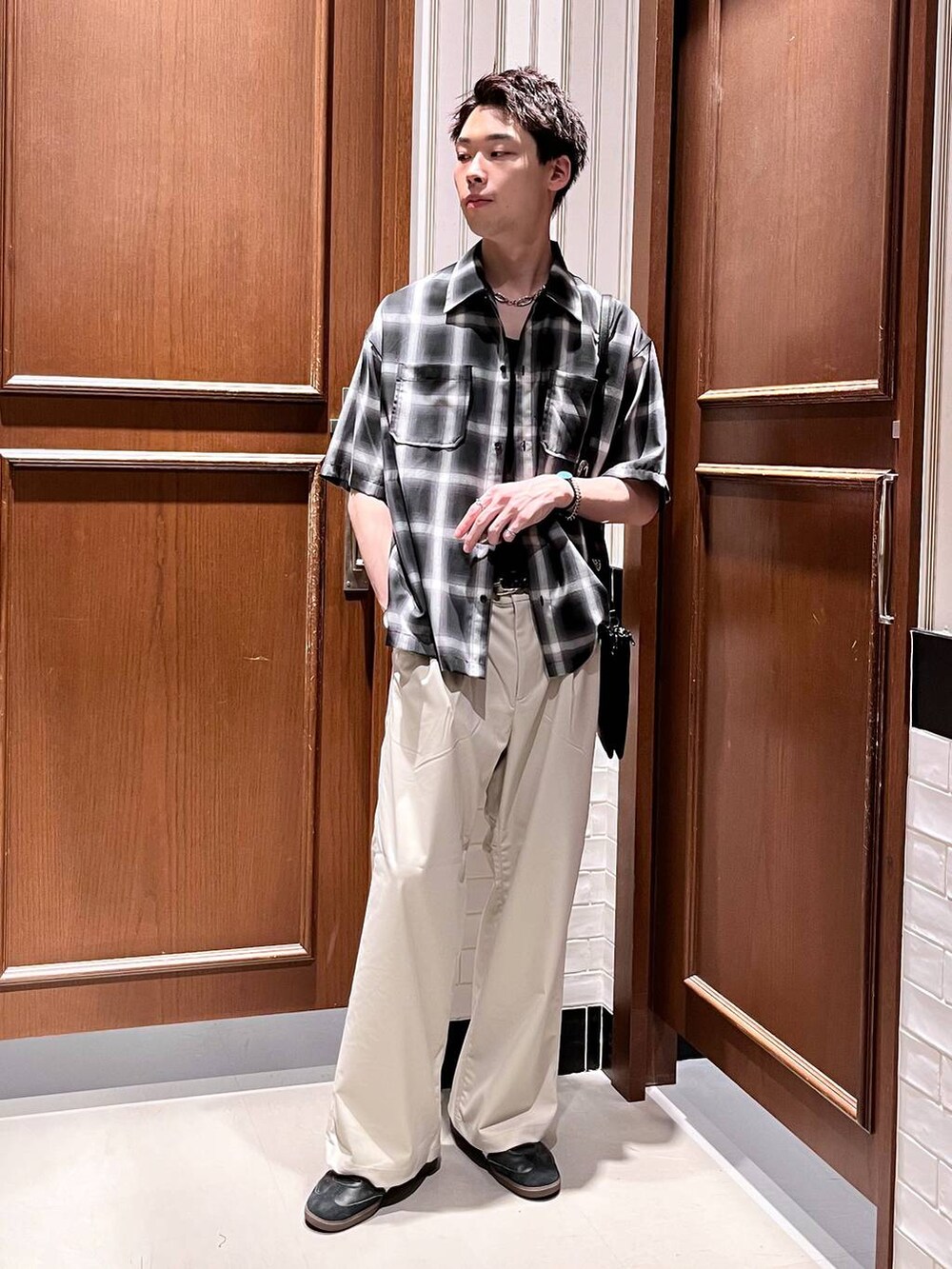 ホワイト系のスラックス、ブラック系のショルダーバッグ、ブラック系のシャツ/ブラウスを着用したメンズの夏コーディネートの2枚目の写真