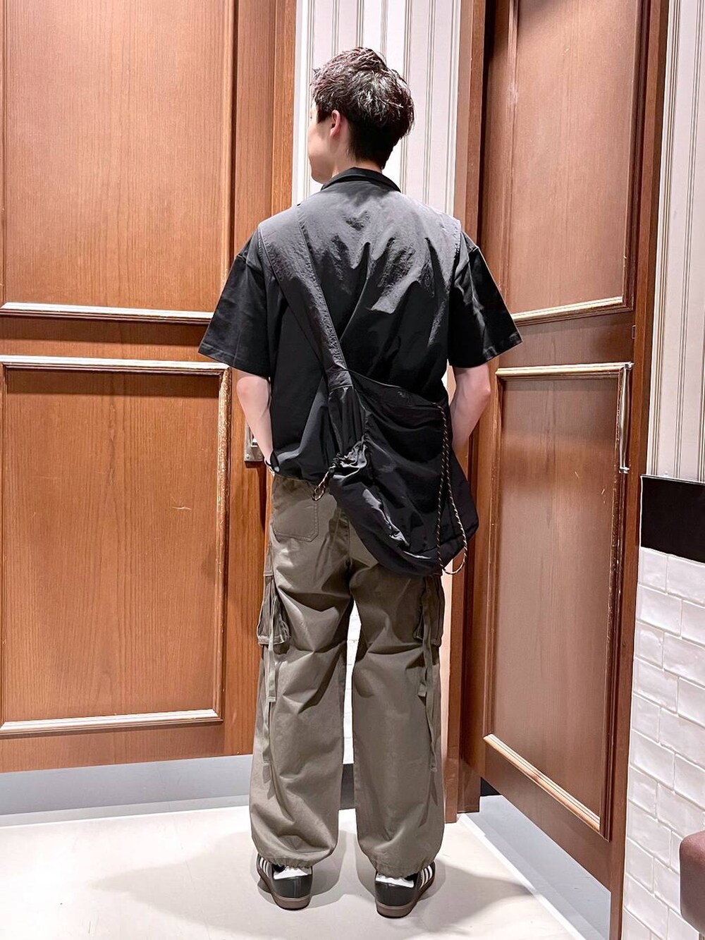 グリーン系のカーゴパンツ、ブラック系のショルダーバッグ、ブラック系のベストを着用したメンズの夏コーディネートの5枚目の写真