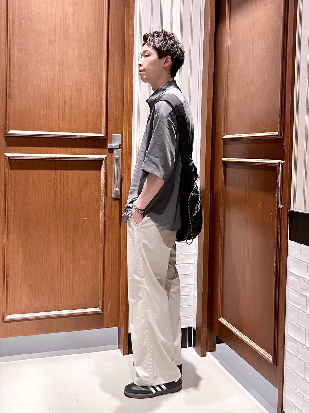 ホワイト系のスラックス、グレー系のシャツ/ブラウス、ブラック系のショルダーバッグを着用したメンズの夏コーディネートの5枚目の写真