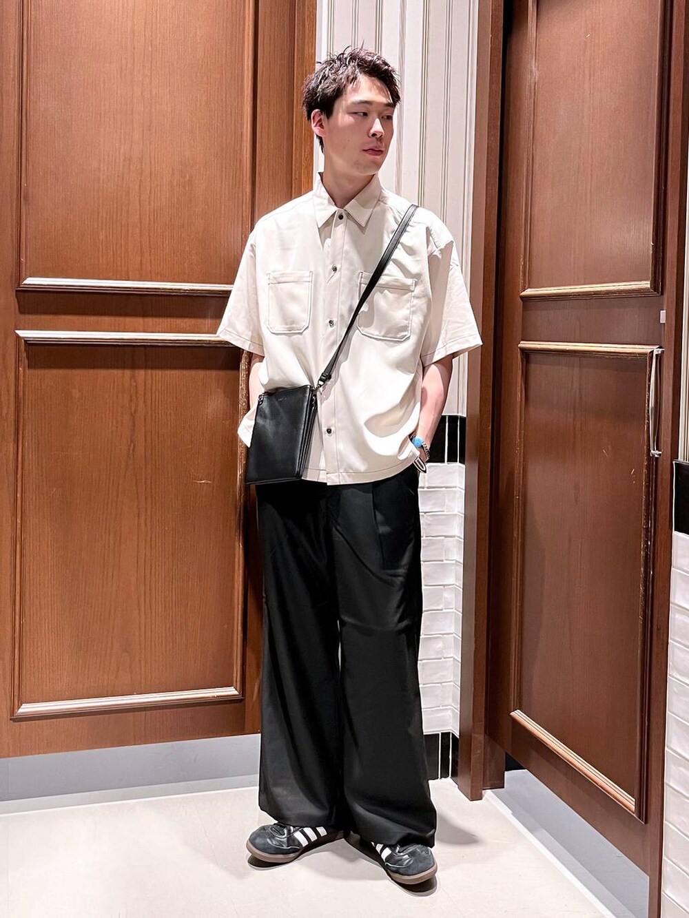 ブラック系のスラックス、ブラック系のショルダーバッグ、ホワイト系のシャツ/ブラウスを着用したメンズの夏コーディネートの6枚目の写真