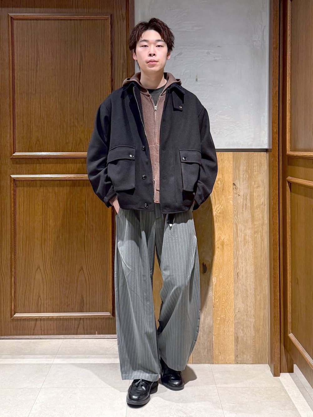 ブラック系のブルゾン、ブラウン系のニット/セーター、グレー系のスラックスを着用したメンズの冬コーディネートの7枚目の写真