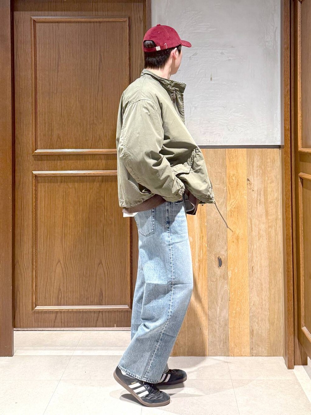 ブルー系のデニムパンツ、グリーン系のモッズコート、ブラウン系のカーディガン/ボレロを着用したメンズの秋コーディネートの7枚目の写真