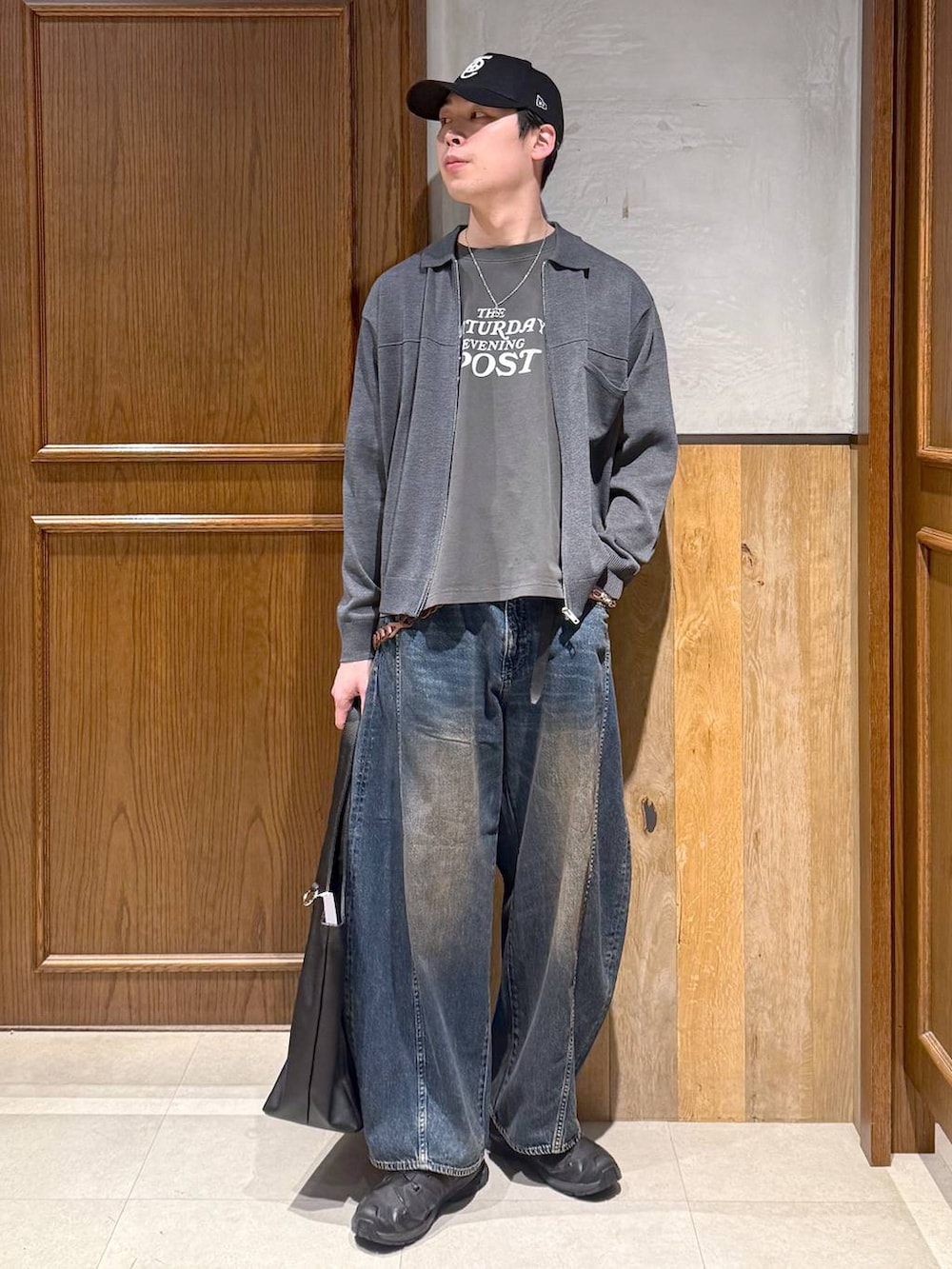 ブラック系のトートバッグ、ブルー系のデニムパンツ、グレー系のTシャツ/カットソーを着用したメンズの春コーディネートの2枚目の写真