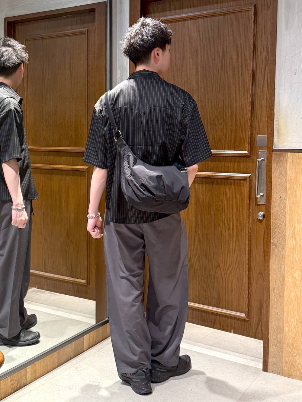 グレー系のスラックス、ブラック系のショルダーバッグ、ホワイト系のTシャツ/カットソーを着用したメンズの春コーディネートの4枚目の写真