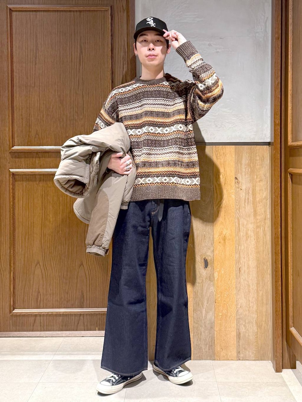 ブルー系のデニムパンツ、ブラウン系のダウンジャケット/コート、ブラウン系のニット/セーターを着用したメンズの冬コーディネートの2枚目の写真