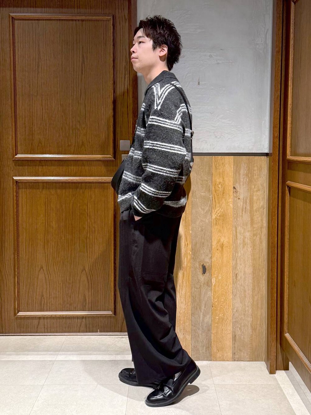 ブラック系のショルダーバッグ、ブラック系のポロシャツ、ブラック系のスラックスを着用したメンズの冬コーディネートの4枚目の写真