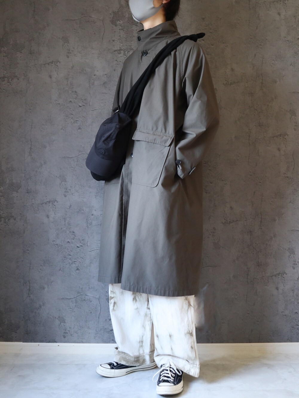 グレー系のトレンチコート、ブラック系のスニーカー、ホワイト系のデニムパンツを着用したメンズの夏コーディネートの2枚目の写真