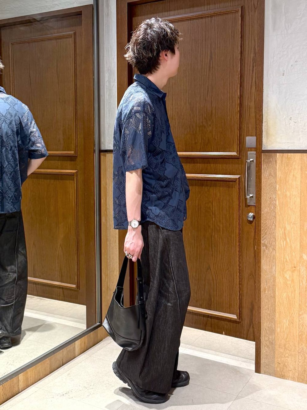 ブラック系のハンドバッグ、ブラック系のデニムパンツ、ブルー系のシャツ/ブラウスを着用したメンズの春コーディネートの4枚目の写真