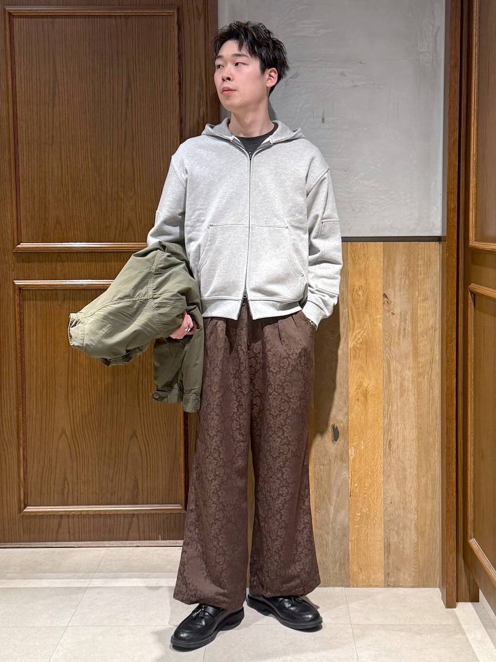 グリーン系のモッズコート、イエロー系のスラックス、グレー系のパーカーを着用したメンズの冬コーディネートの2枚目の写真