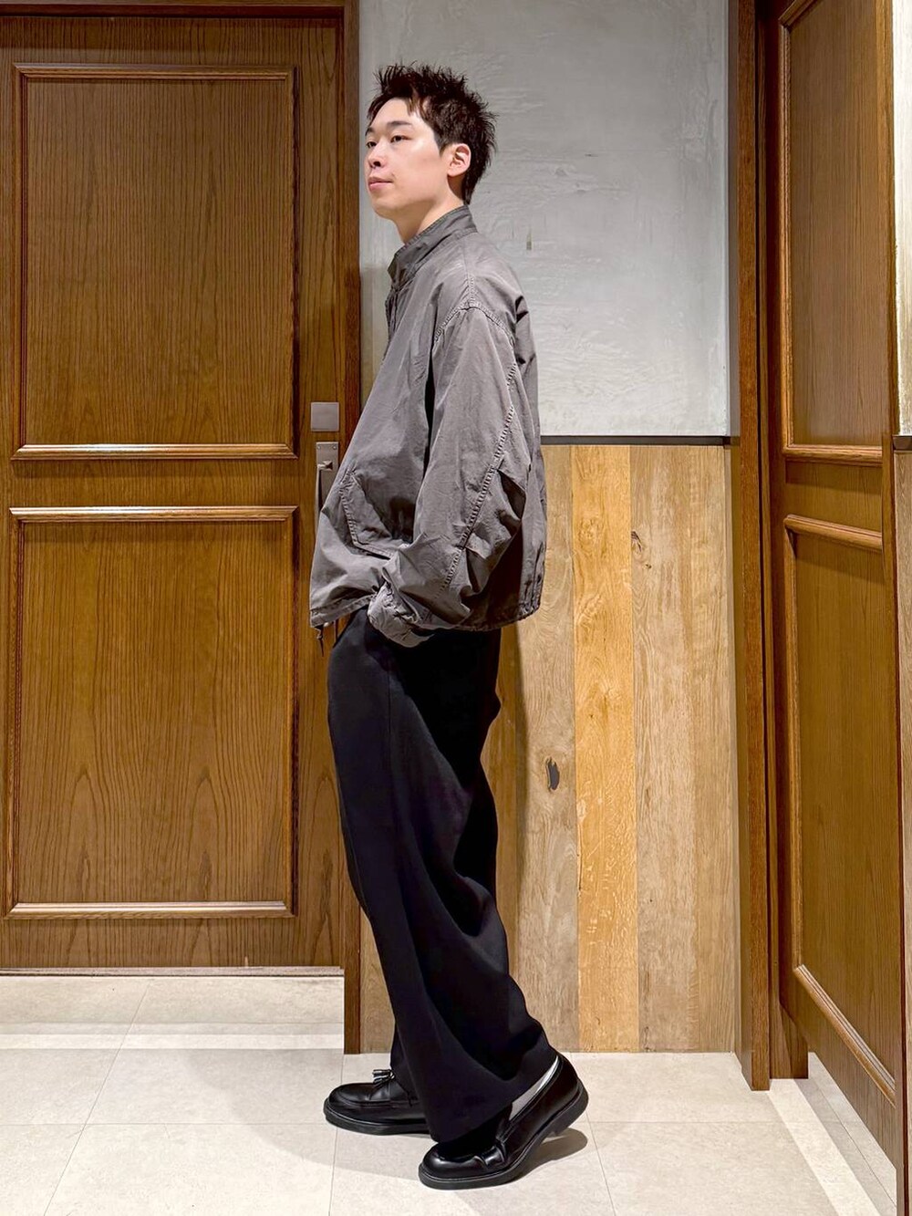 グレー系のモッズコート、ブラック系のスラックス、ブラウン系のスウェットを着用したメンズの秋コーディネートの4枚目の写真